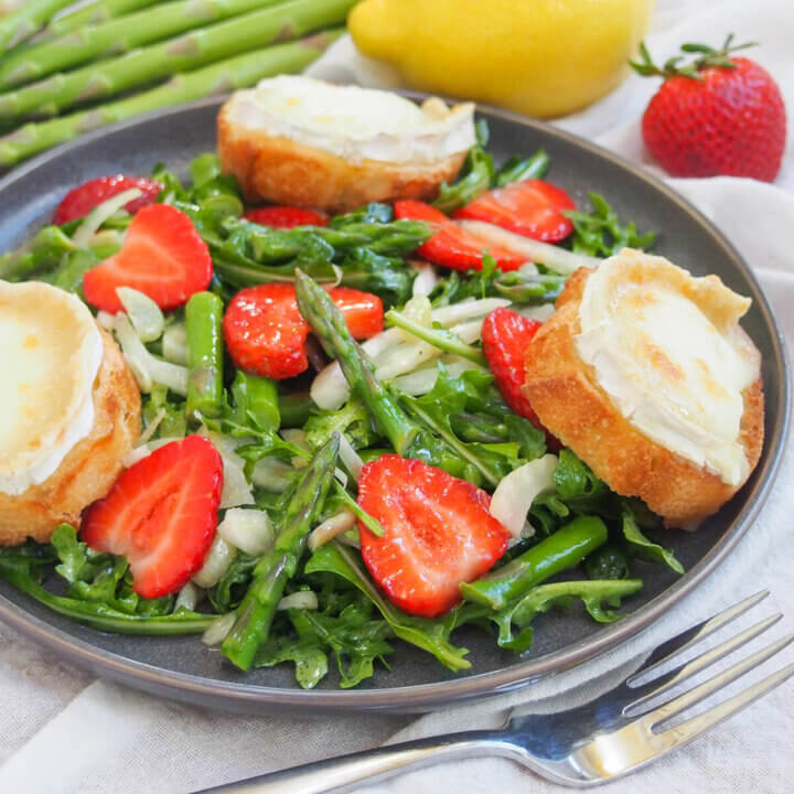 side view of plate of strawberry asparagus salad with fork in front