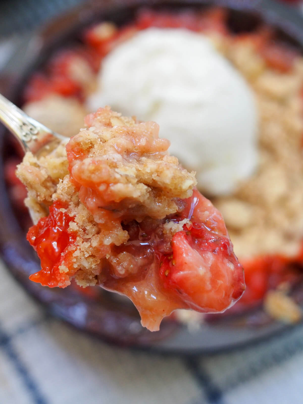 spoonful of strawberry rhubarb crisp spoonful of strawberry rhubarb crisp help over dish in background