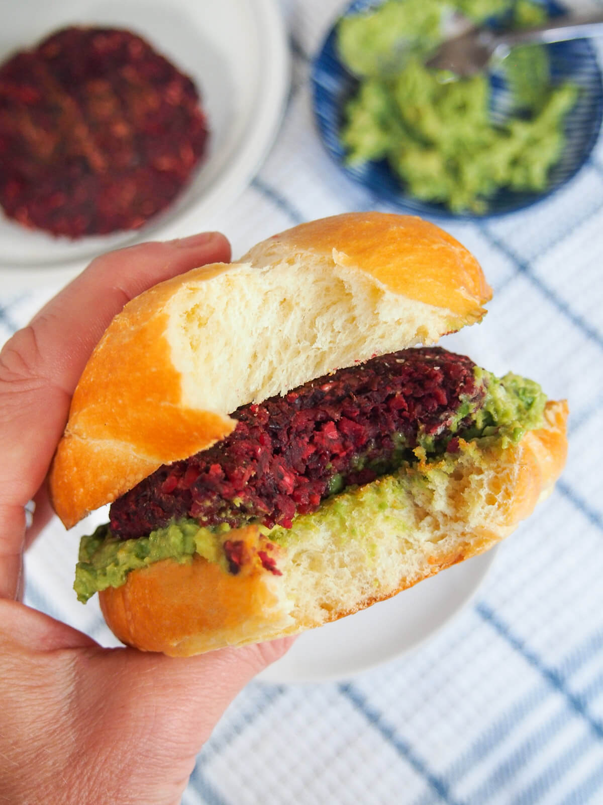 holding a black bean beet burger in hand with bite out of the burger