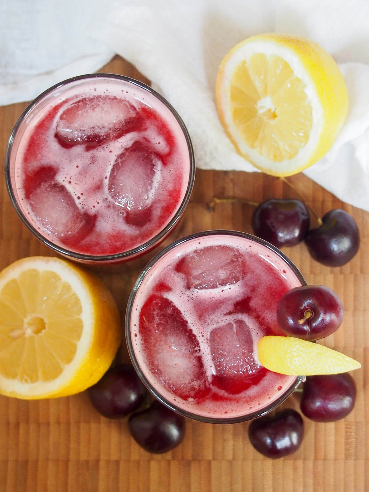 overhead view of two glasses with cherries and cut lemons to either side