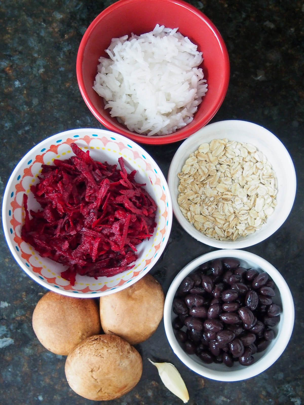 bowls of beet, rice, oats, black beans with mushrooms and garlic to side
