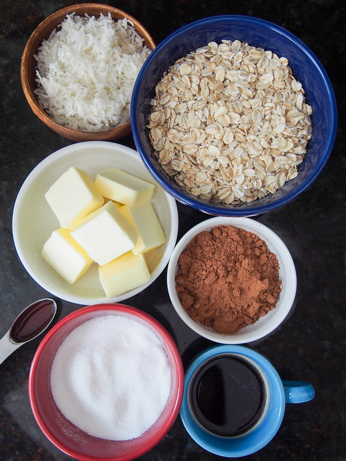 bowls of oats, butter, coconut, cocoa powder, sugar and small cup of coffee