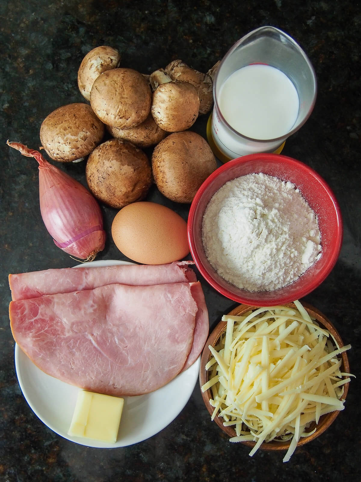 milk, flour, cheese, ham and butter in dishes with mushrooms, shallot and egg to side
