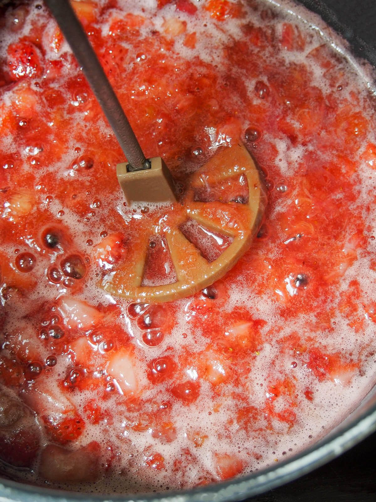 mashing jam mixture in pot