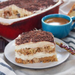 slice of panettone tiramisu on plate with coffee and rest of dish behind