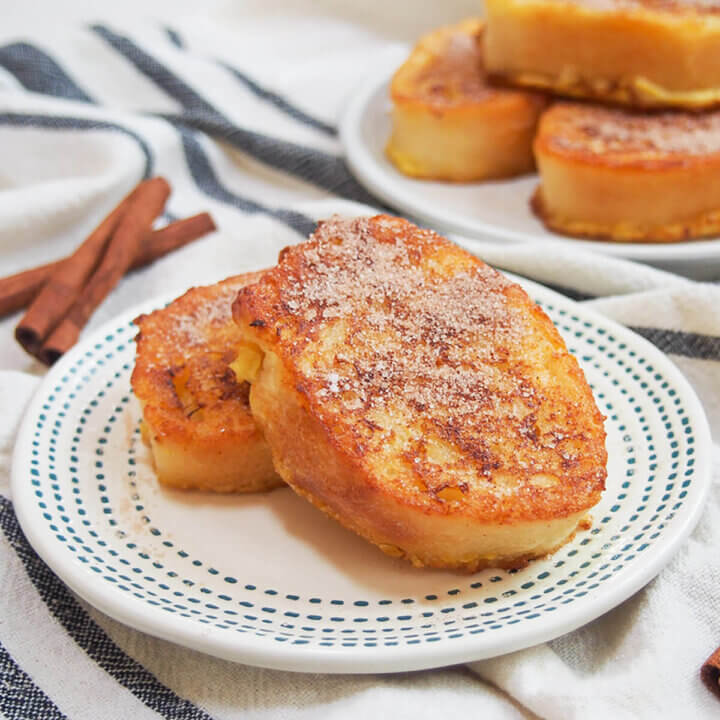 two pieces of torrijas on a plate topped with cinnamon sugar