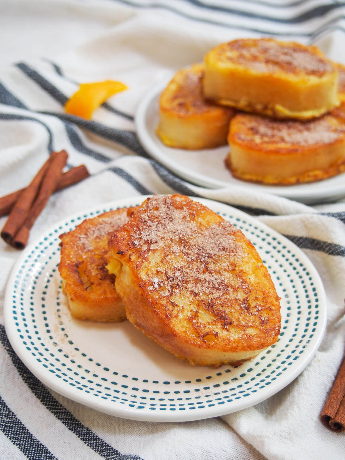 pieces of torrijas on plate with stack on plate behind