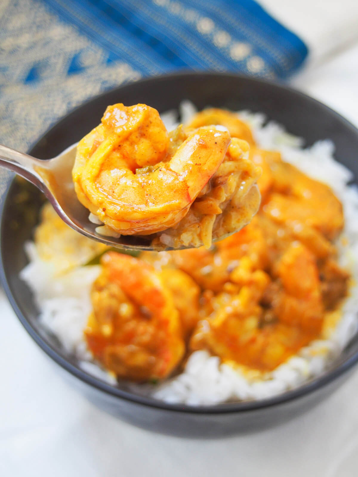 holding a spoonful of shrimp and rice above bowl