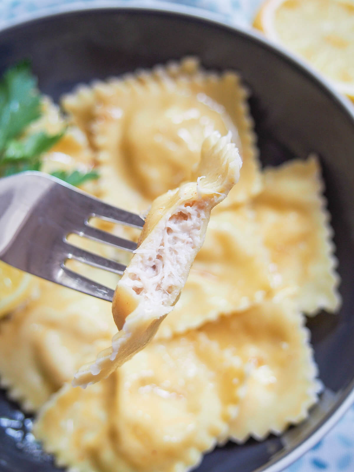 holding a bitten crab ravioli over a bowl