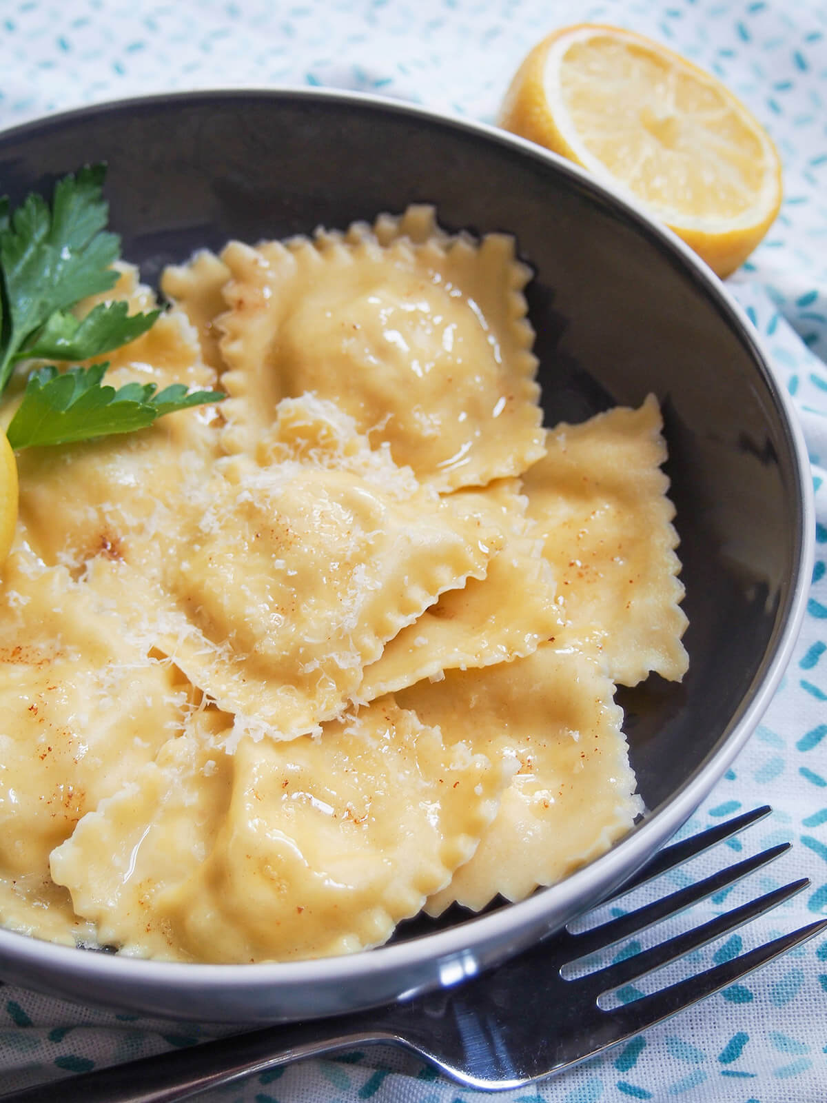 plate of crab ravioli from the side with cut lemon behind