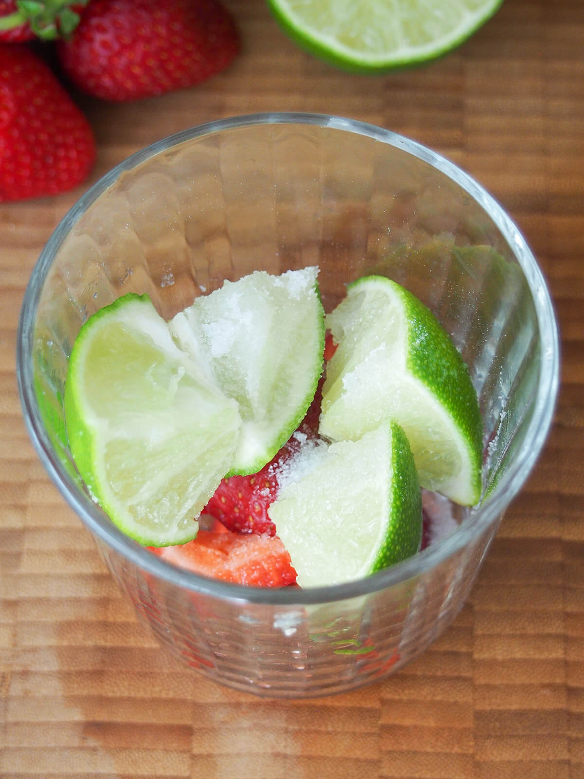 chunks of lime and strawberry in glass with sugar over top