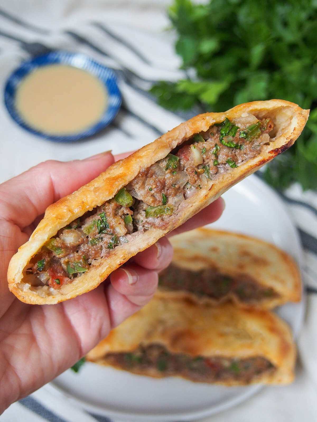holding a hawawshi meat filled pita in hand