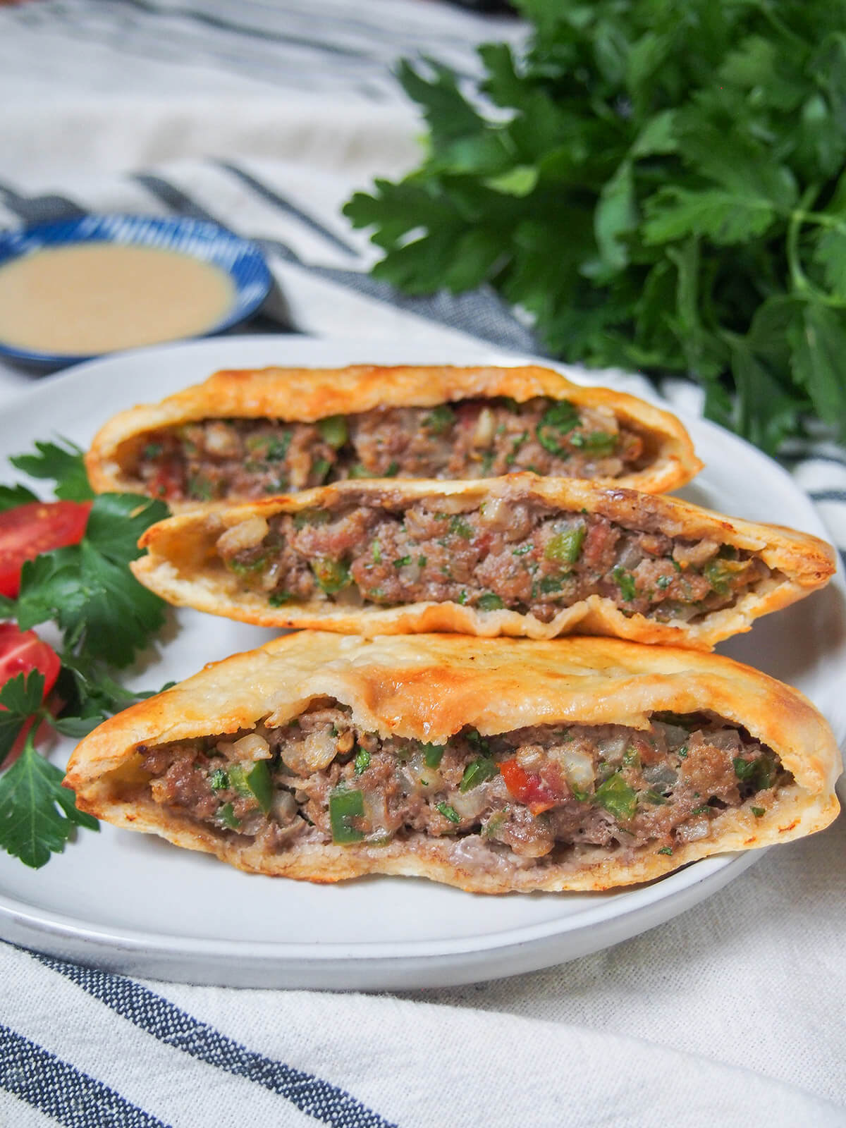 three hawawshi meat filled pita on plate
