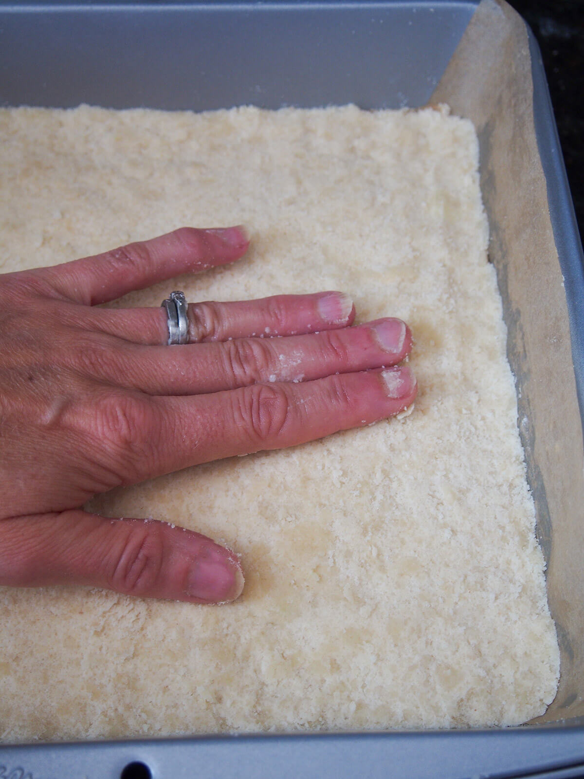 pressing shortbread base into lined baking tin