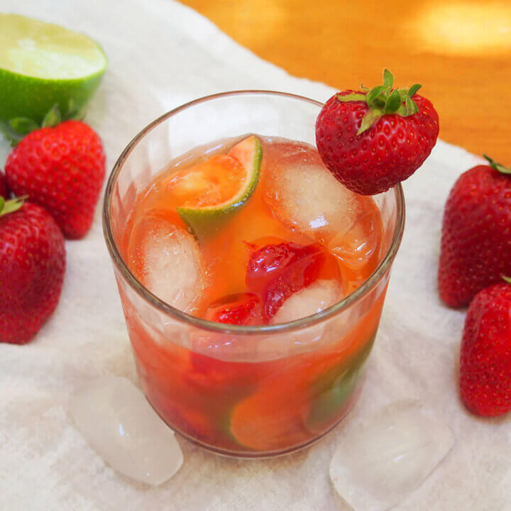 glass of strawberry caipirinha with strawberry garnish