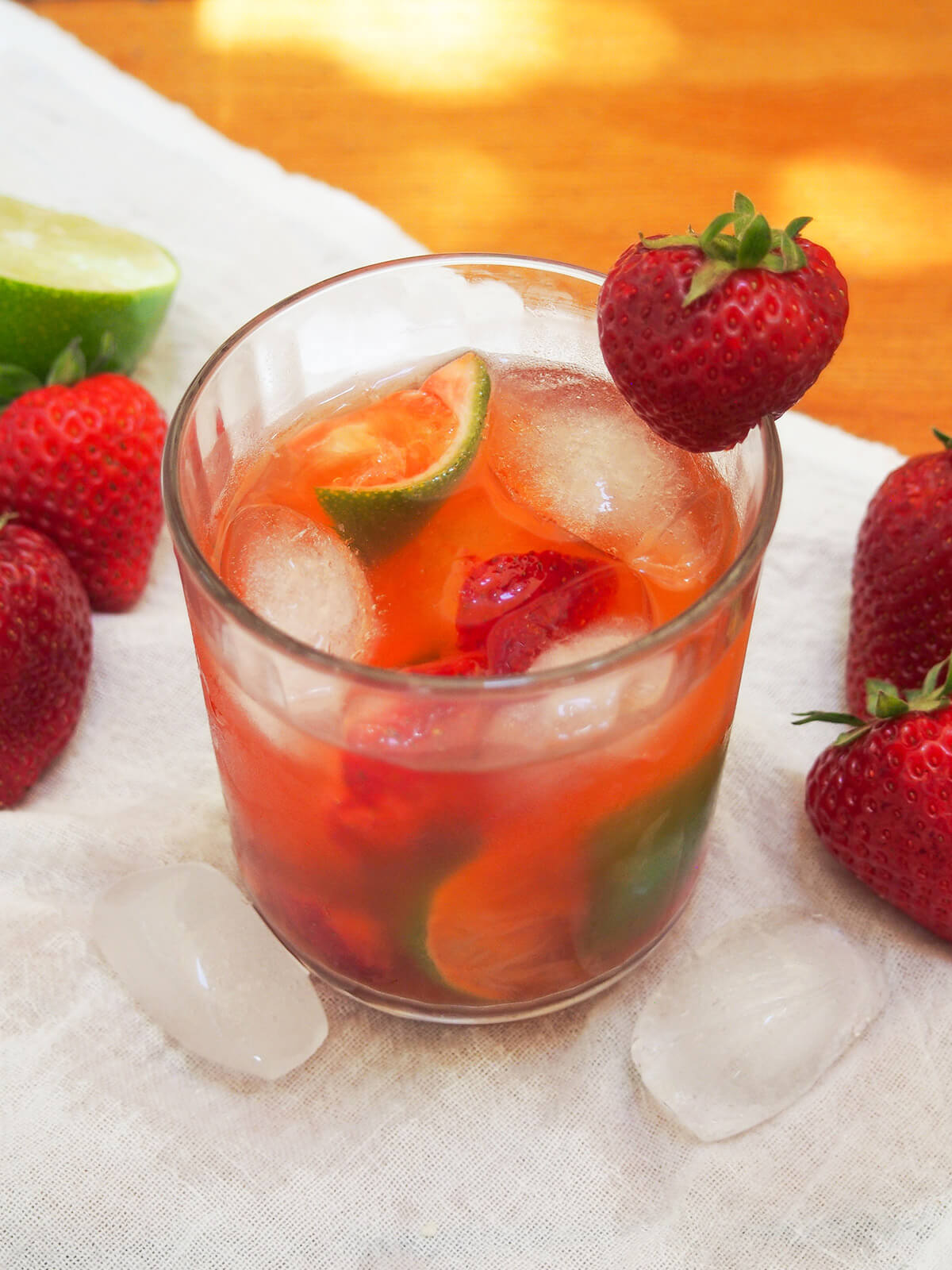 glass of strawberry caipirinha with fruit to either side