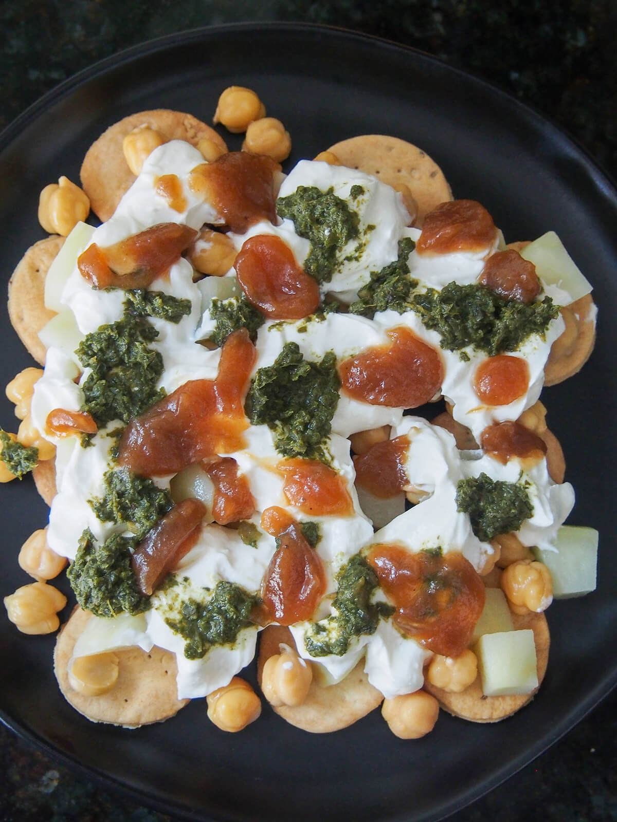 overhead view of plate with crackers, potato and chickpea topped with yogurt and chutneys