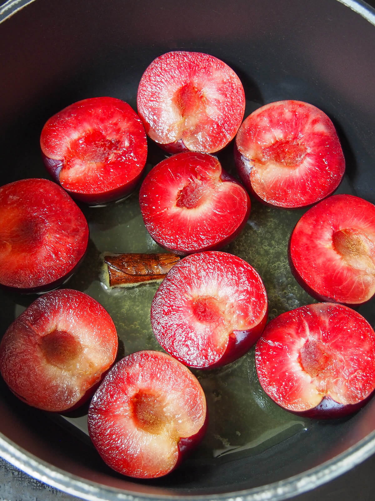 adding halved plums to overage and cinnamon syrup