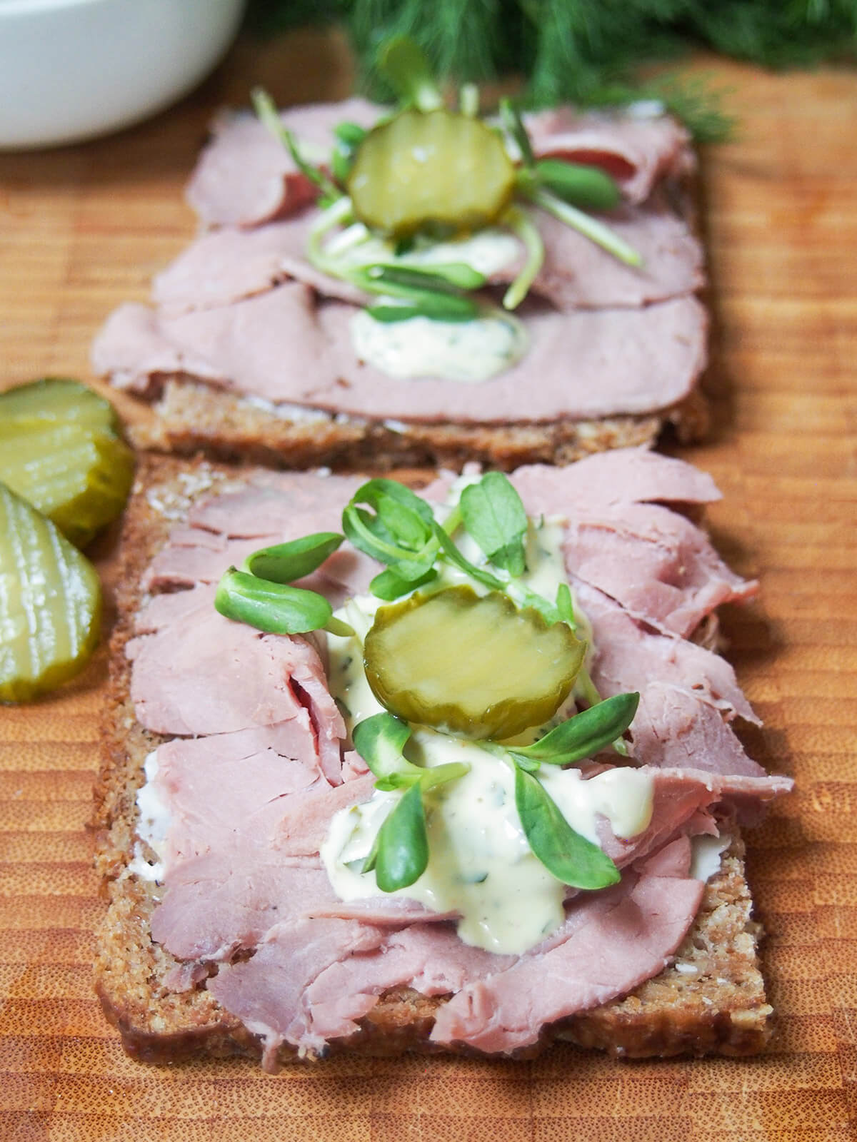 roast beef open sandwich topped with remoulade and a pickle slice