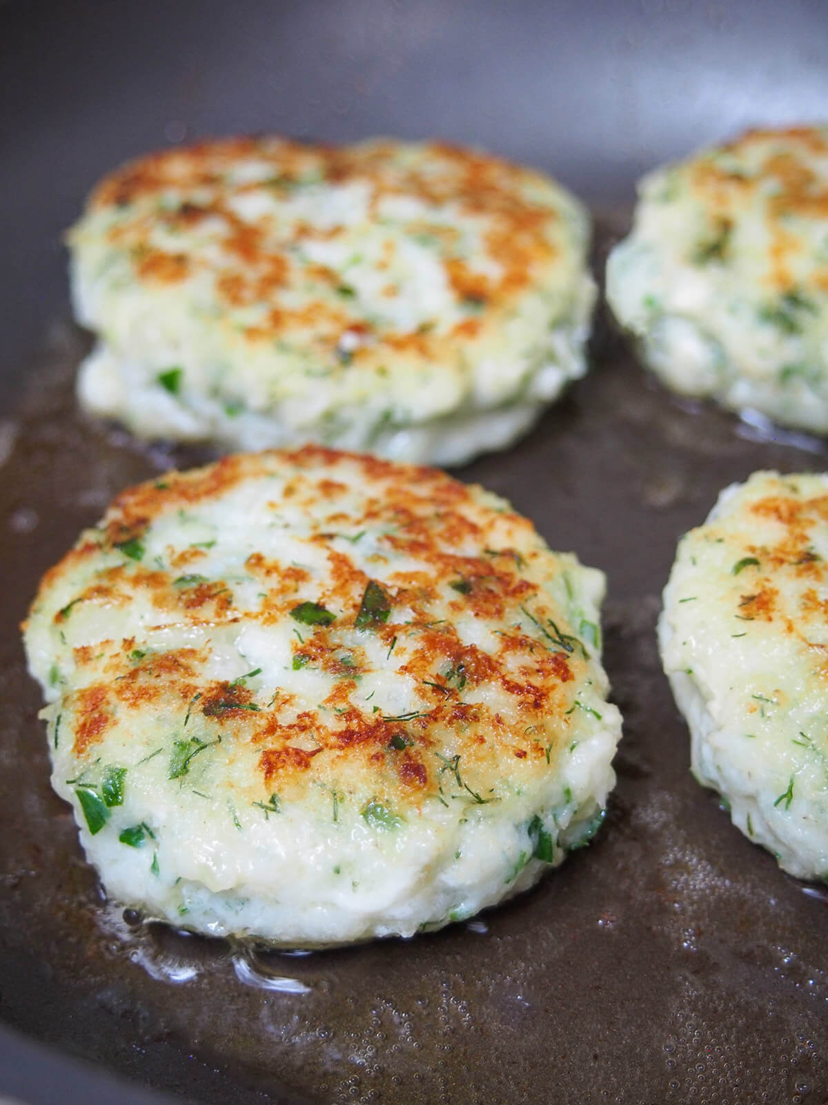 cooking fiskefrikadeller (Danish fish cakes) cooking second side of fish cakes in skillet with tops browned