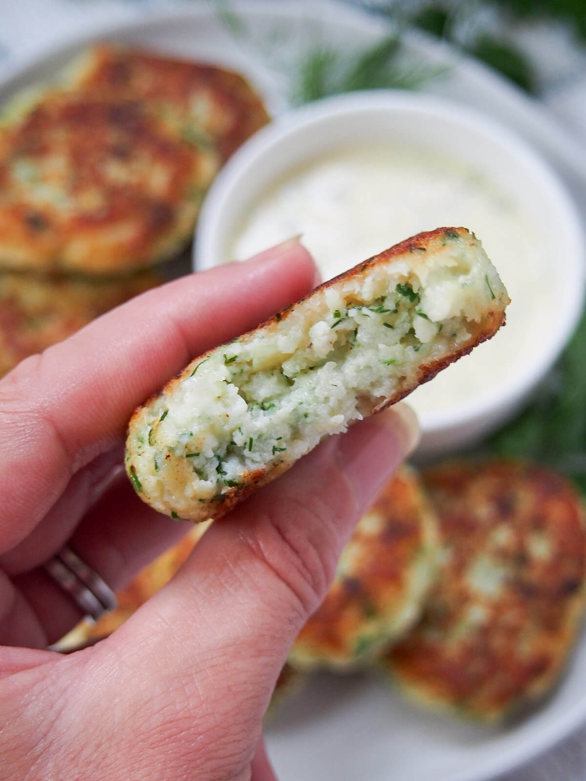 fiskefrikadeller (Danish fish cakes) holding a fish cake in hand with a bite in it showing inside