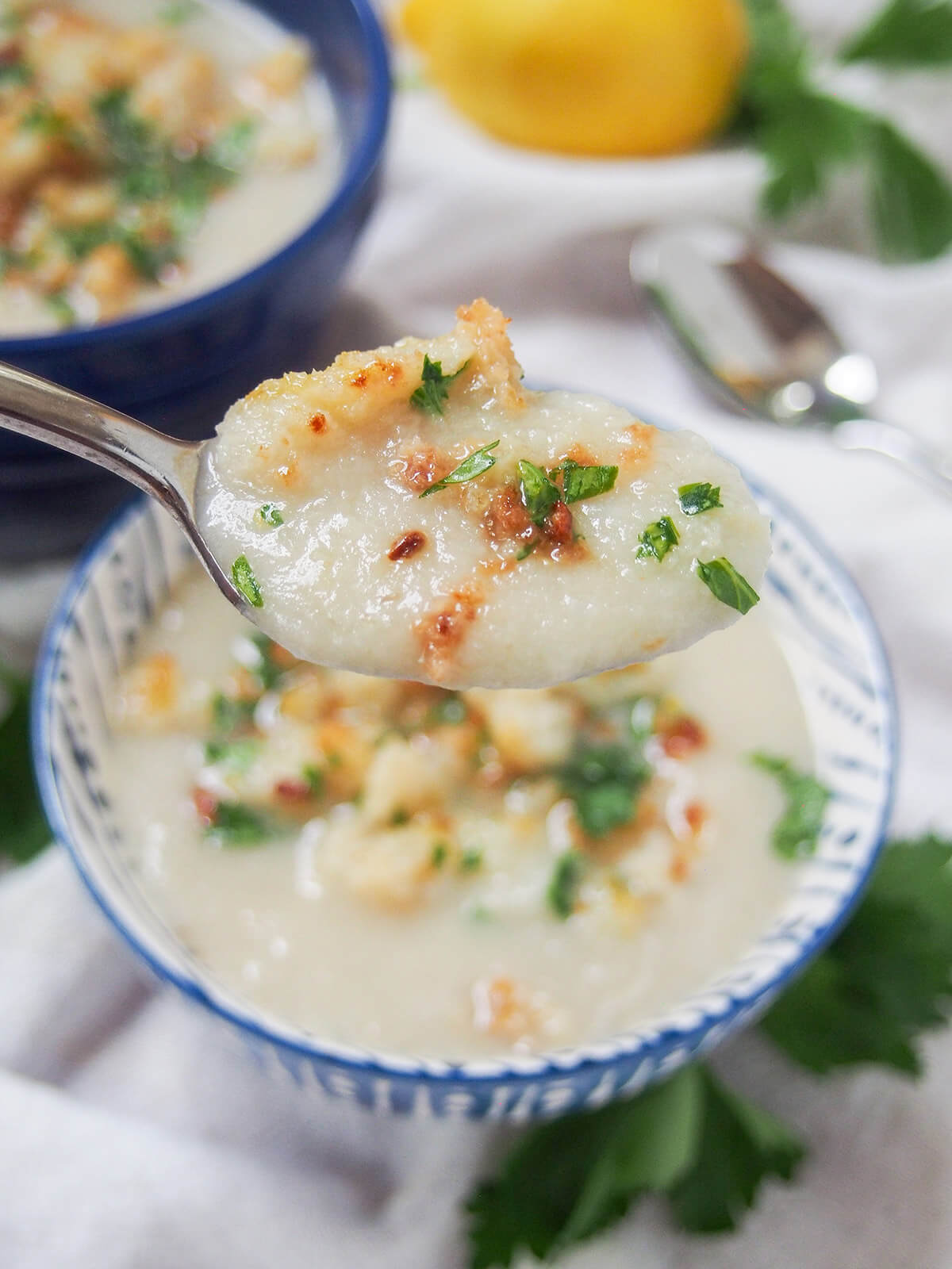 spoonful of Jerusalem artichoke soup being held above bowl