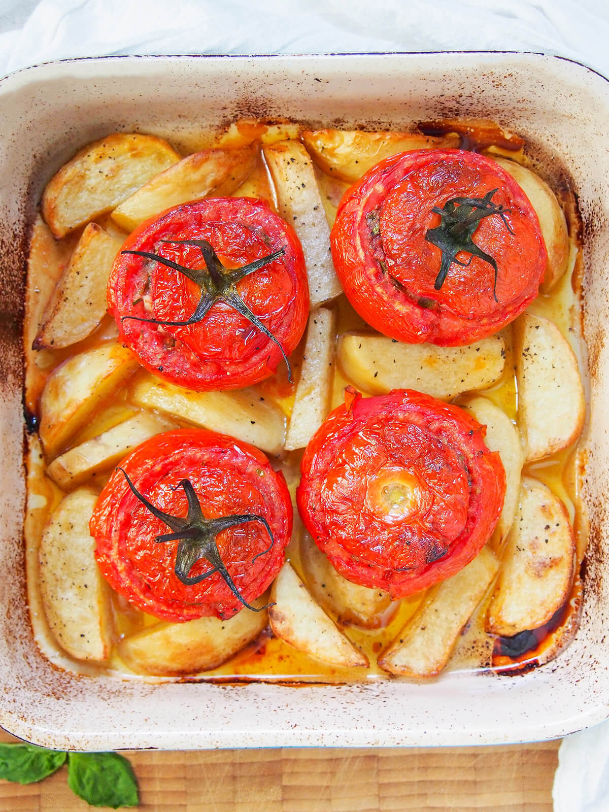 overhead view of tomatoes stuffed with rice in baking dish with potatoes around tomatoes