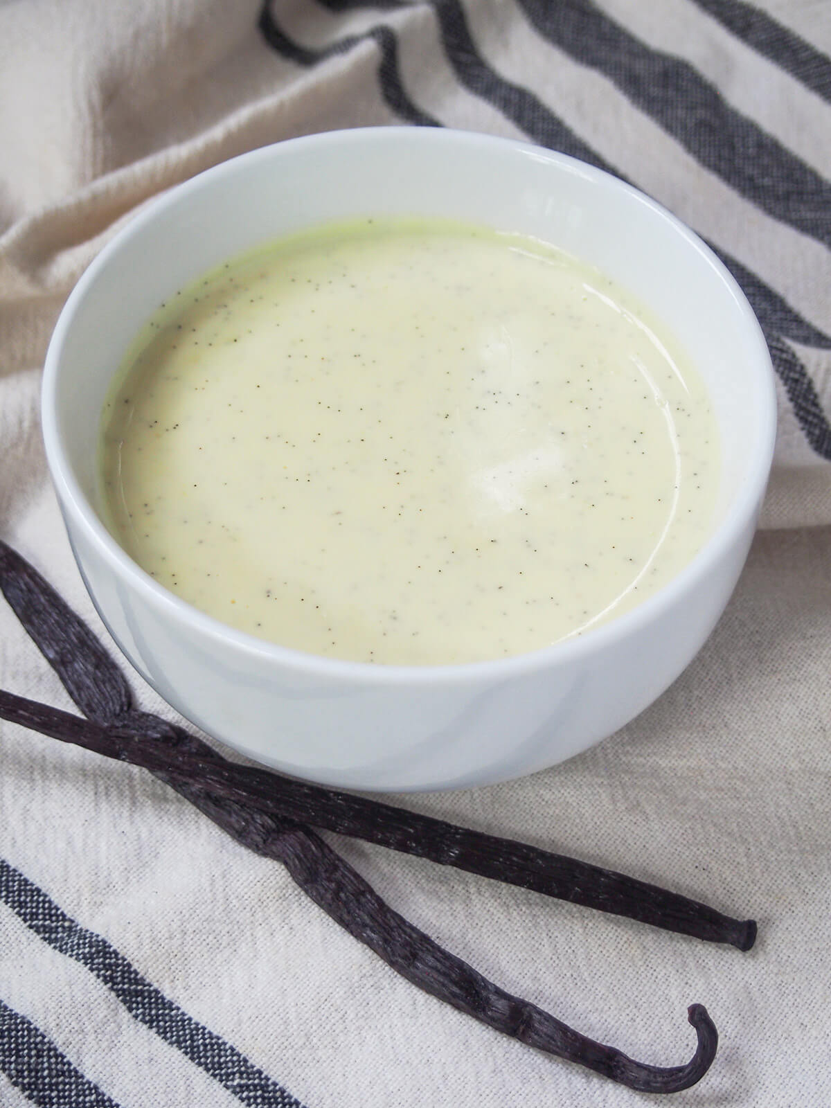 bowl of Vanillesosse German vanilla sauce with curled vanilla pod below