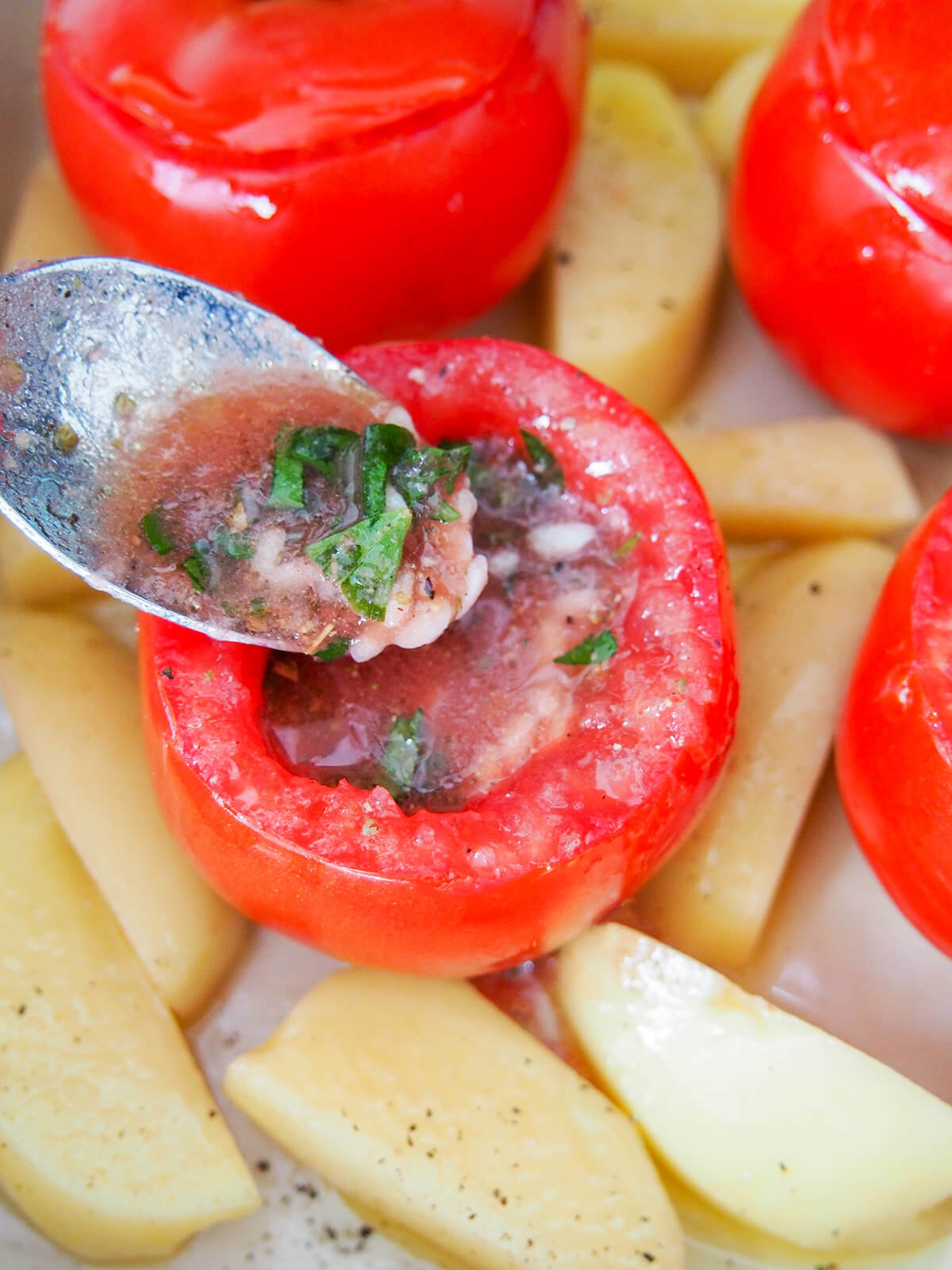 adding rice and tomato juice filling to a hollowed out tomato