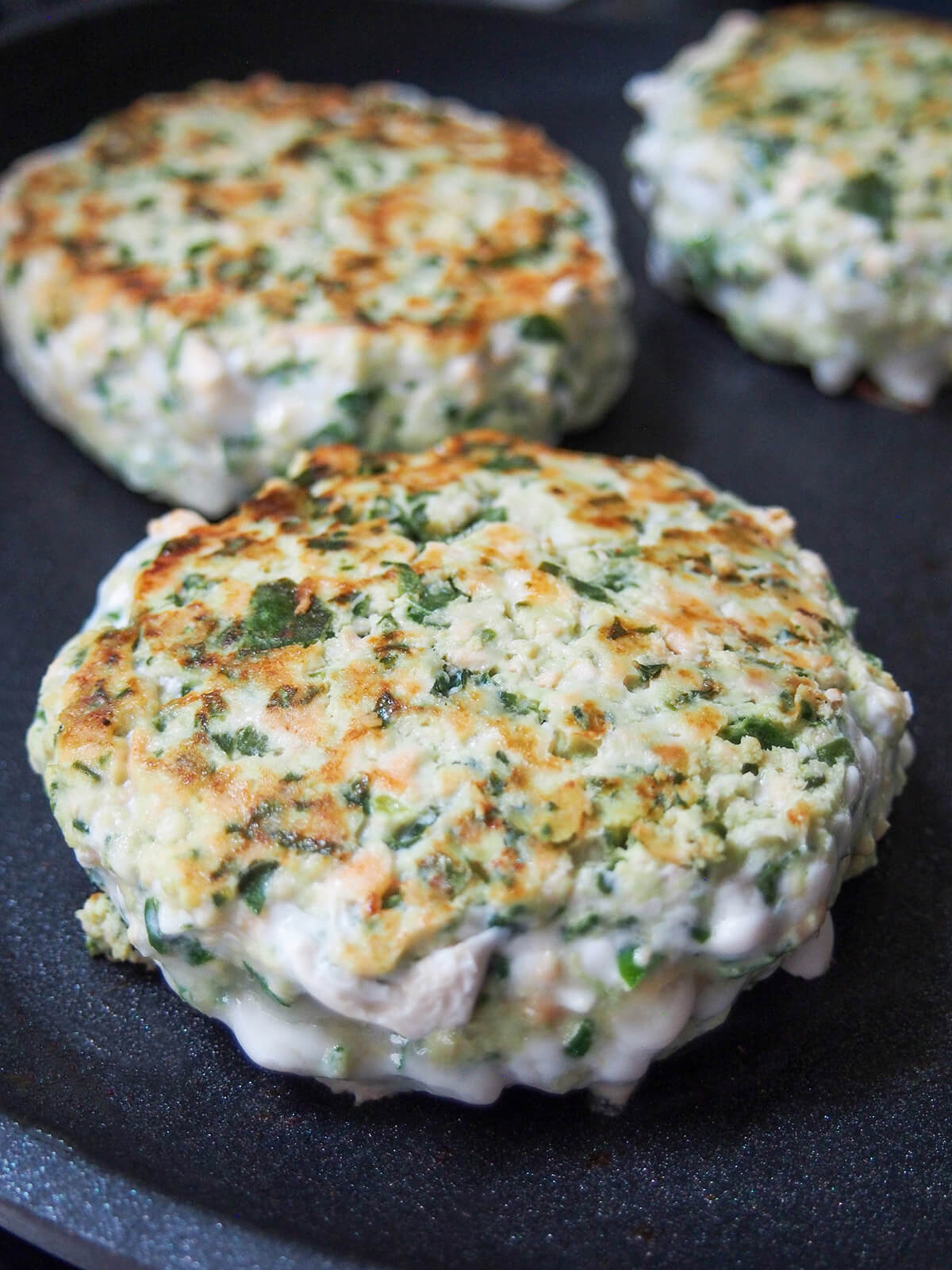 cooking spinach feta salmon burgers in skillet