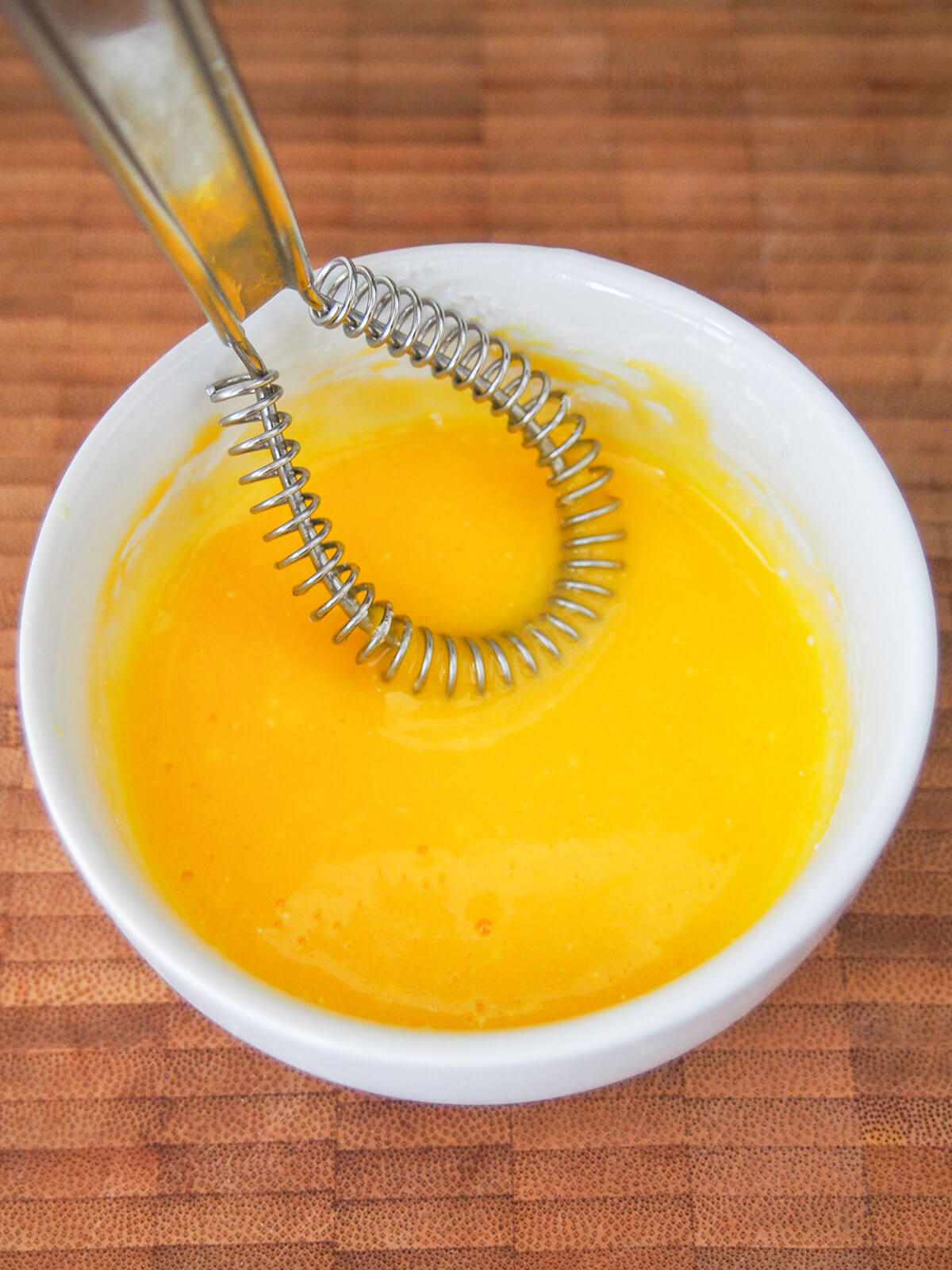 egg yolk whisked with corn starch in small bowl with whisk in mixture
