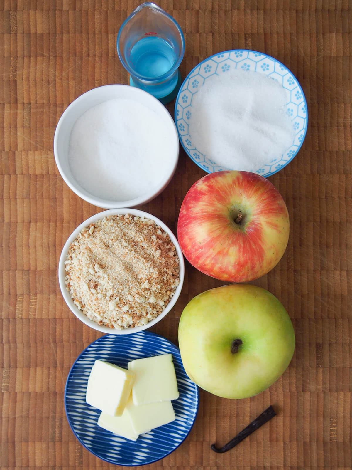 bowls of sugar, breadcrumbs, butter and apples with part vanilla pod at bottom