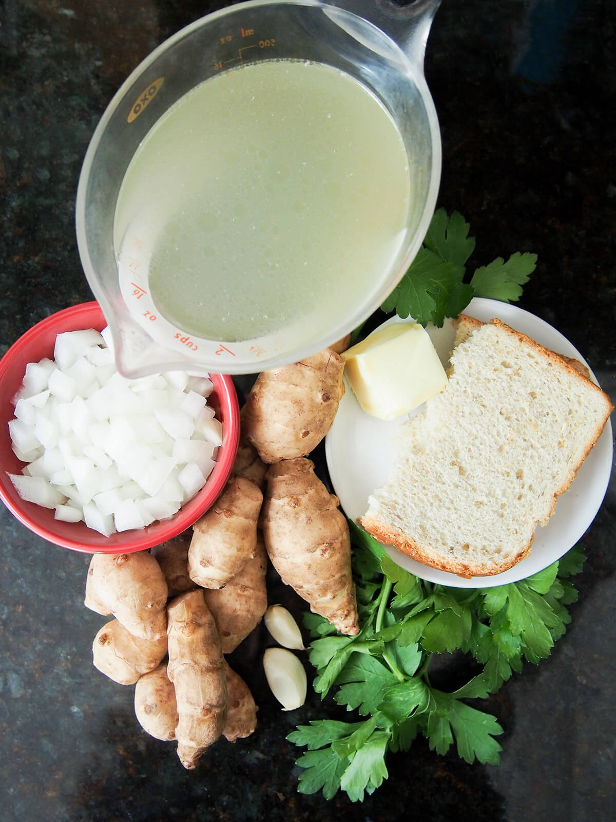 bowl of onion, measure with stock, bread, butter, Jerusalem artichokes and parsley around