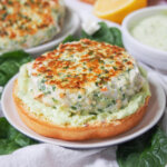 spinach feta salmon burger on bun with avocado crema