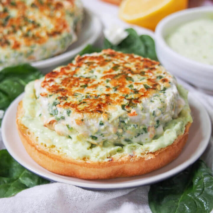 spinach feta salmon burger on bun with avocado crema