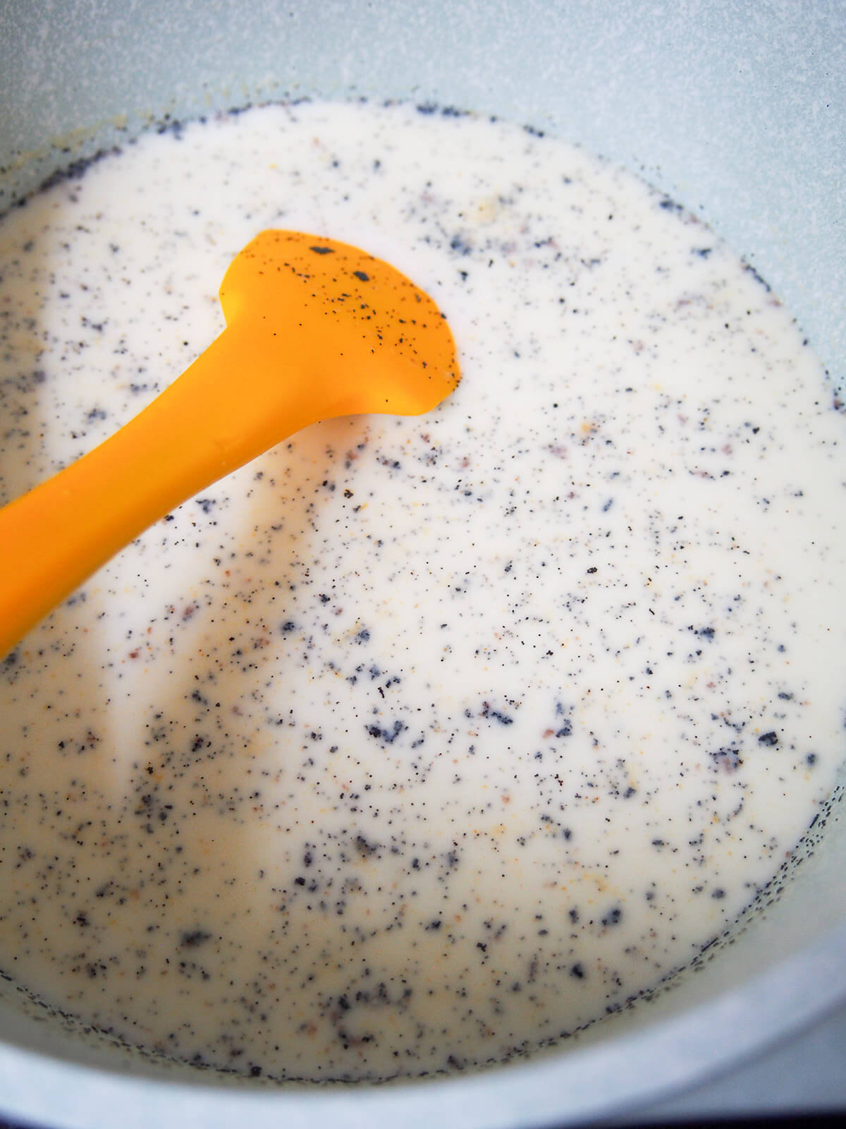 stirring warm milk with vanilla seeds floating on top