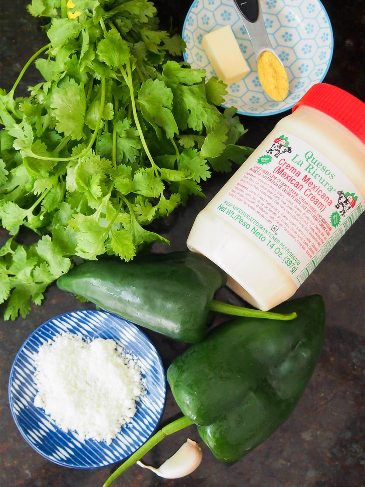 bunch of cilantro, poblano peppers, jar of Mexican crema and cheese, garlic, butter and stock granules to side