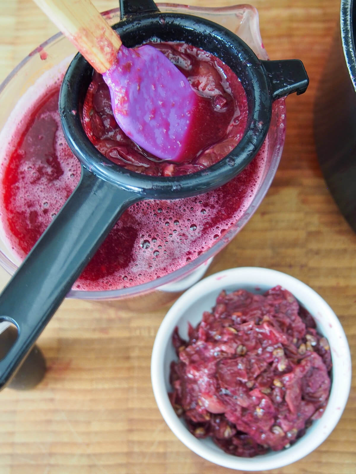 pressing grapes through a strainer to remove seeds and skins.