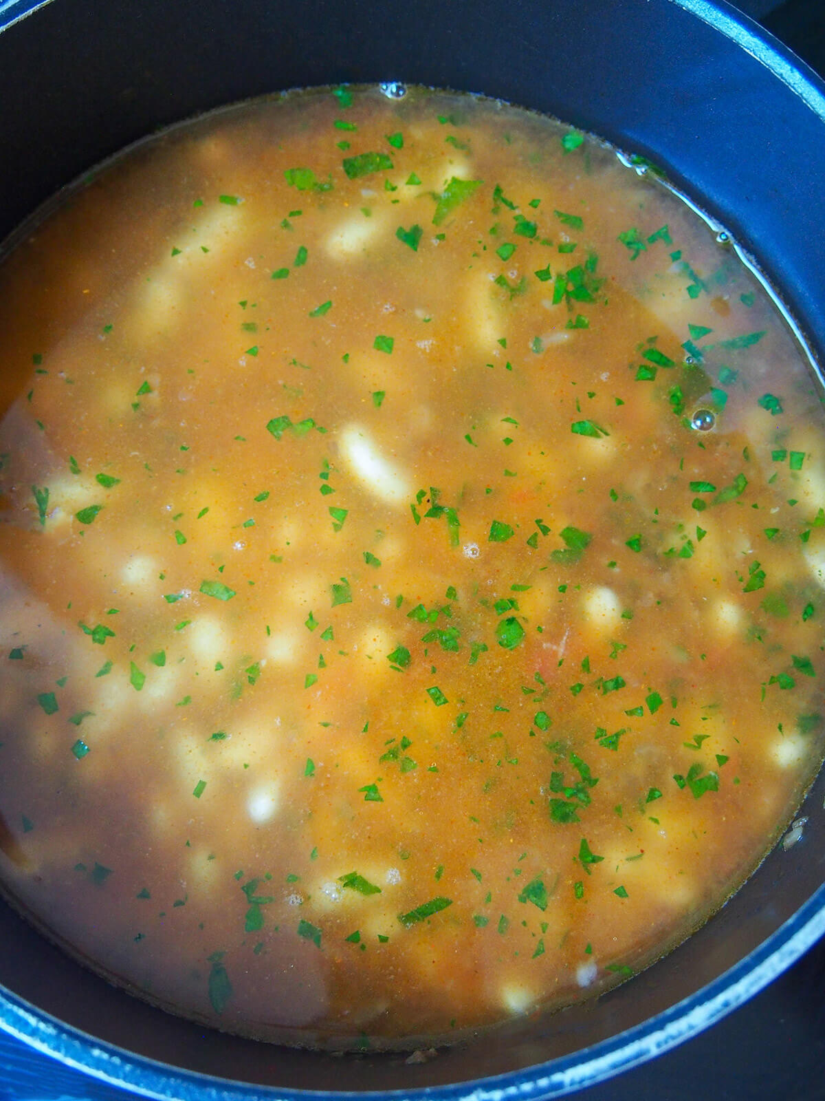 pot with beans under tomato based broth before simmering.