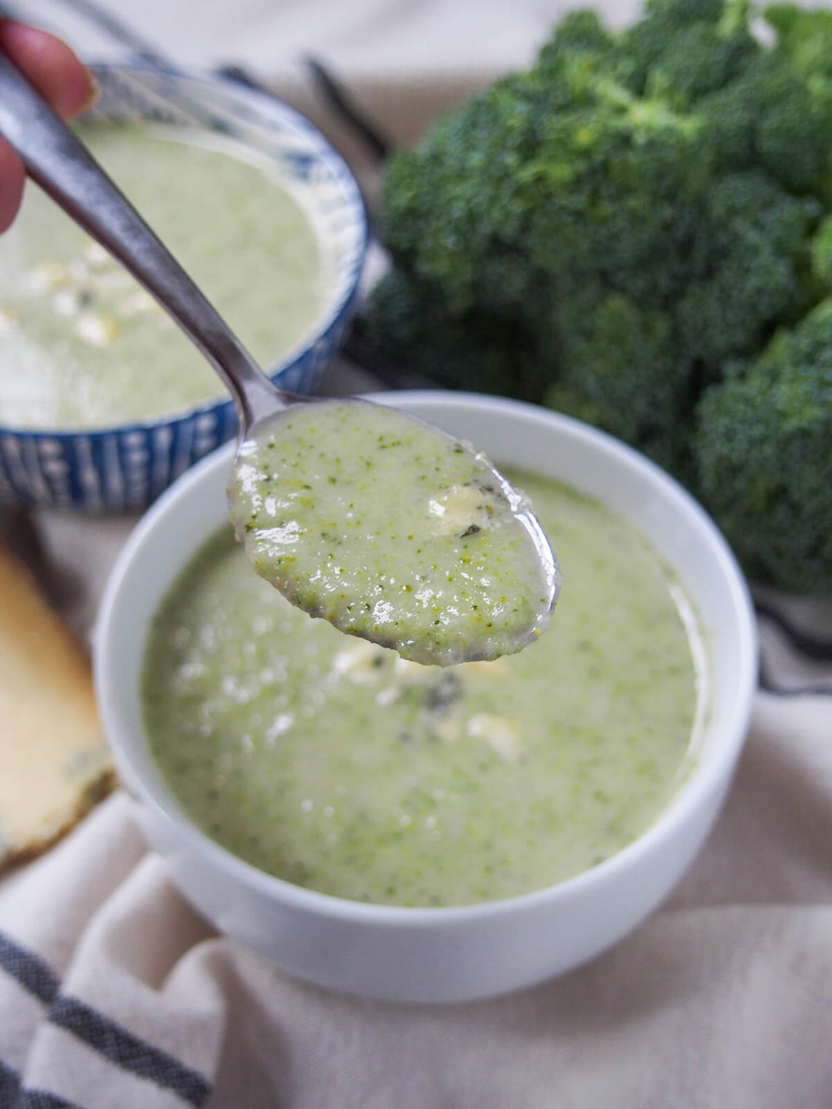 holding a spoonful of broccoli and stilton soup over bowl.