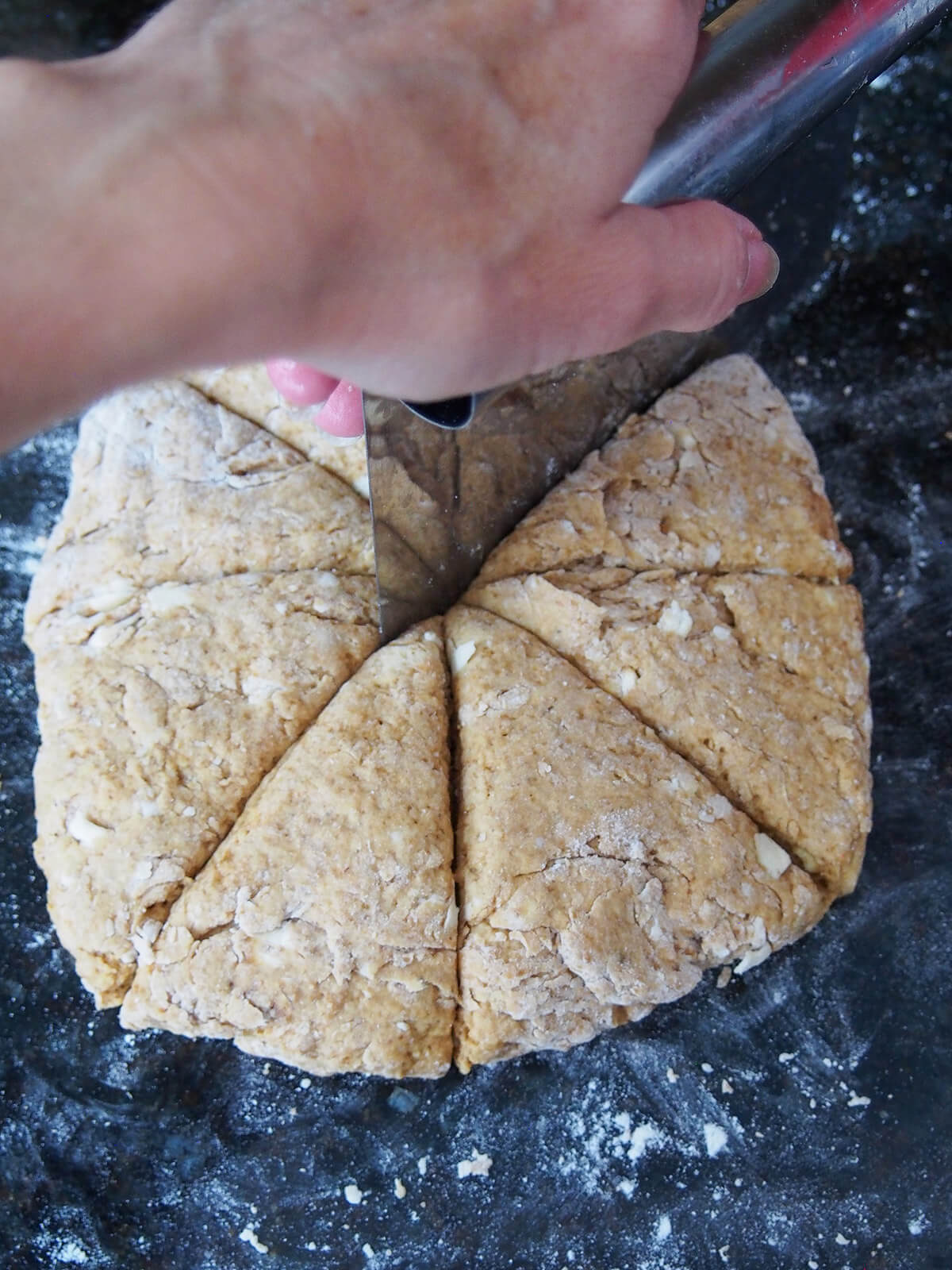 cutting round of gingerbread scone dough into triangles.