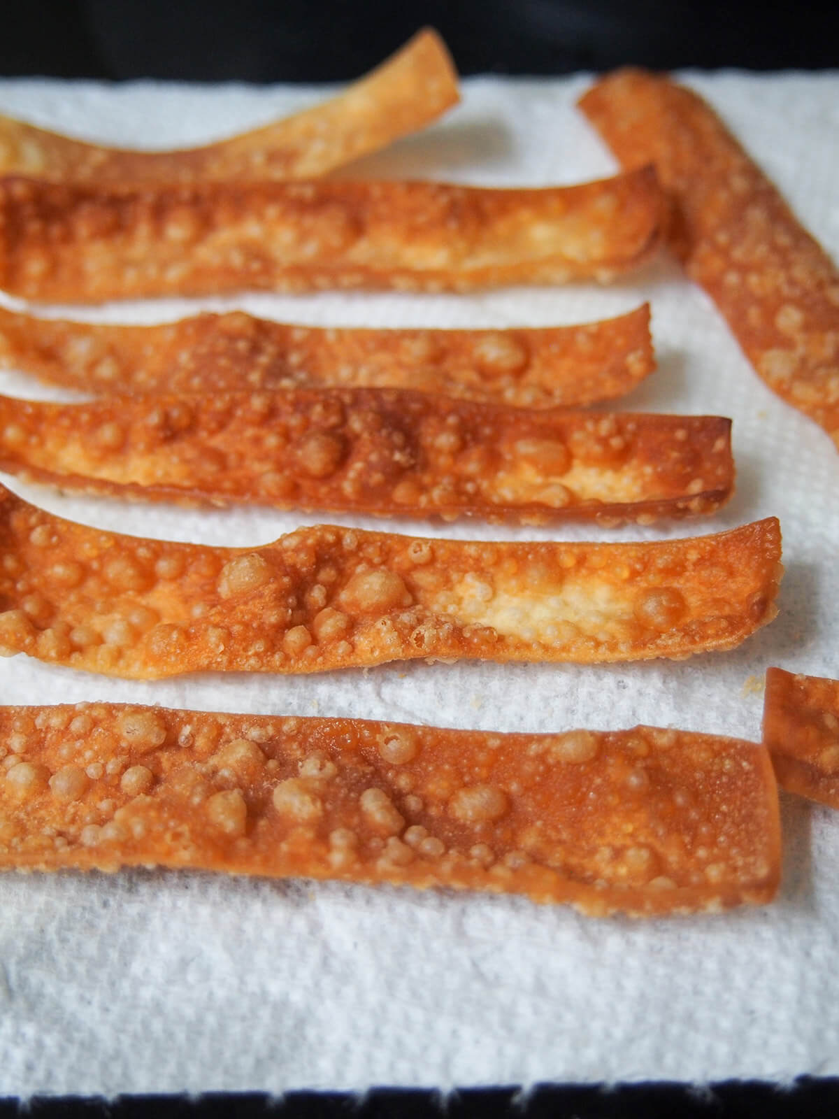 fried wonton strips draining on kitchen paper.
