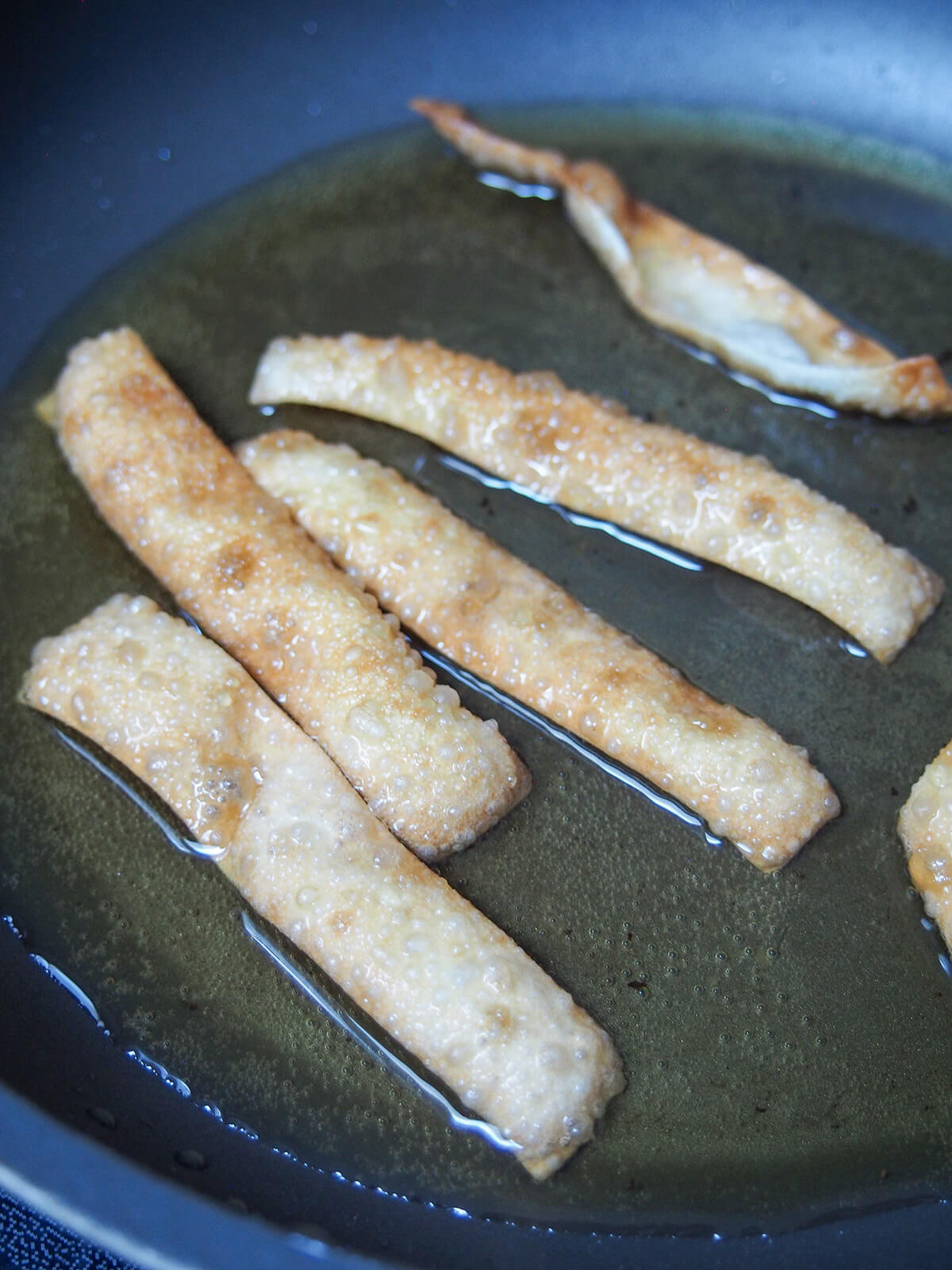 frying strips of wonton wrappers in oil.