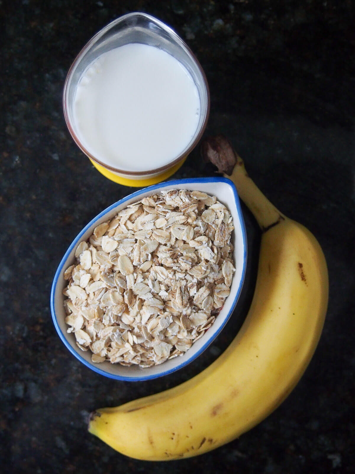 bowl of oats with banana below and measure with milk above from overhead.