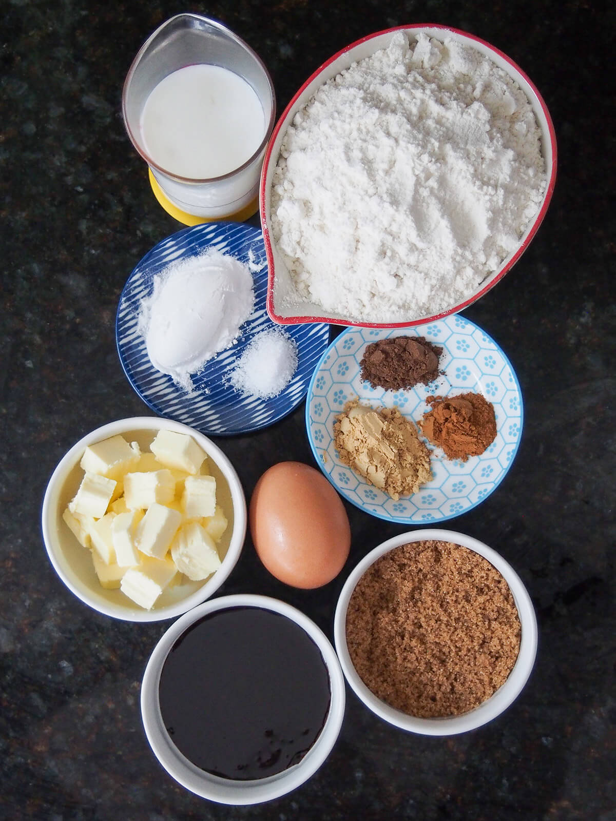 bowls of flour, spices, sugar, butter, milk and molasses.