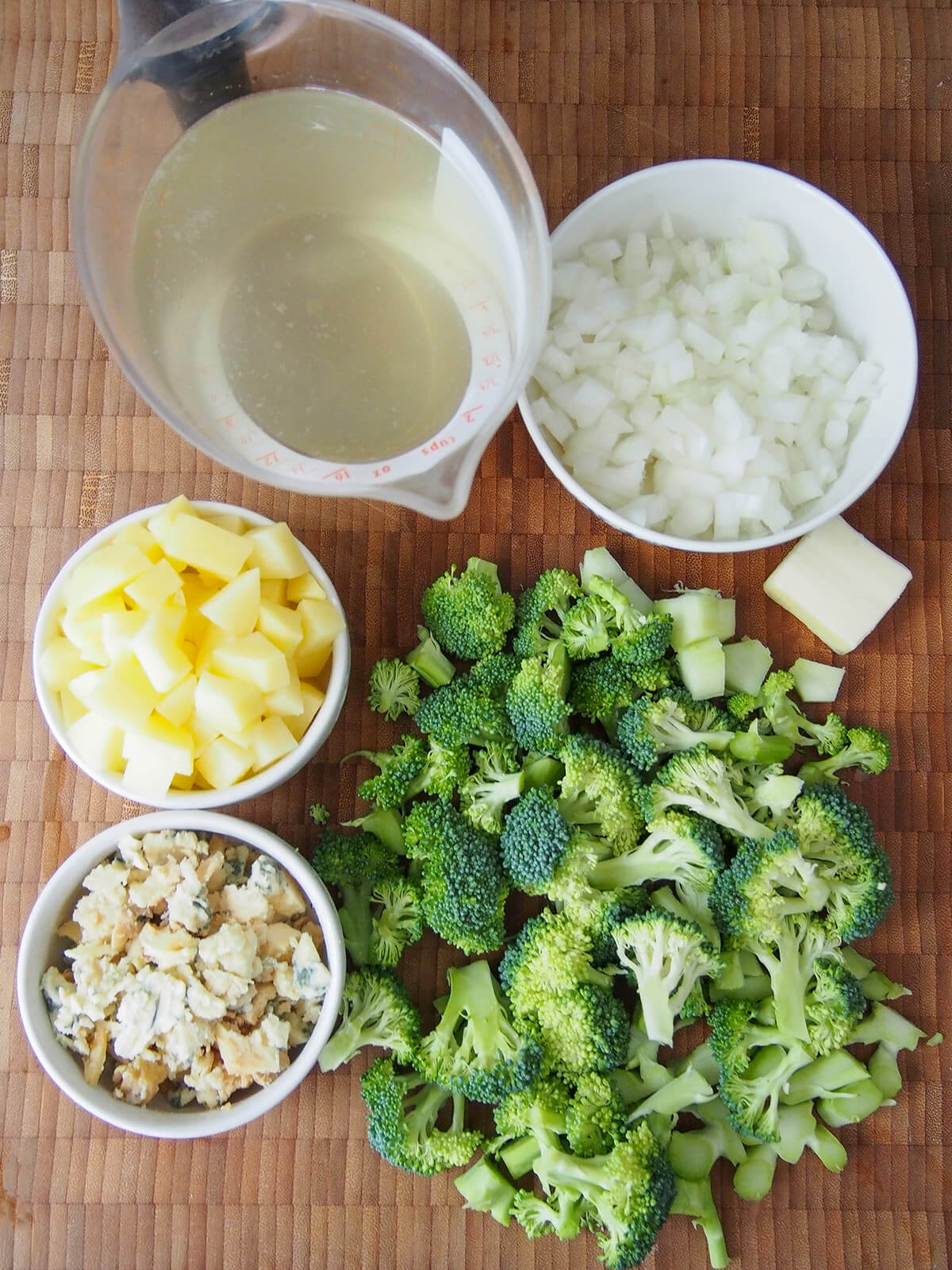 bowls of choped onion, potato, crumbled stilton with chopped broccoli on board and measure with stock.