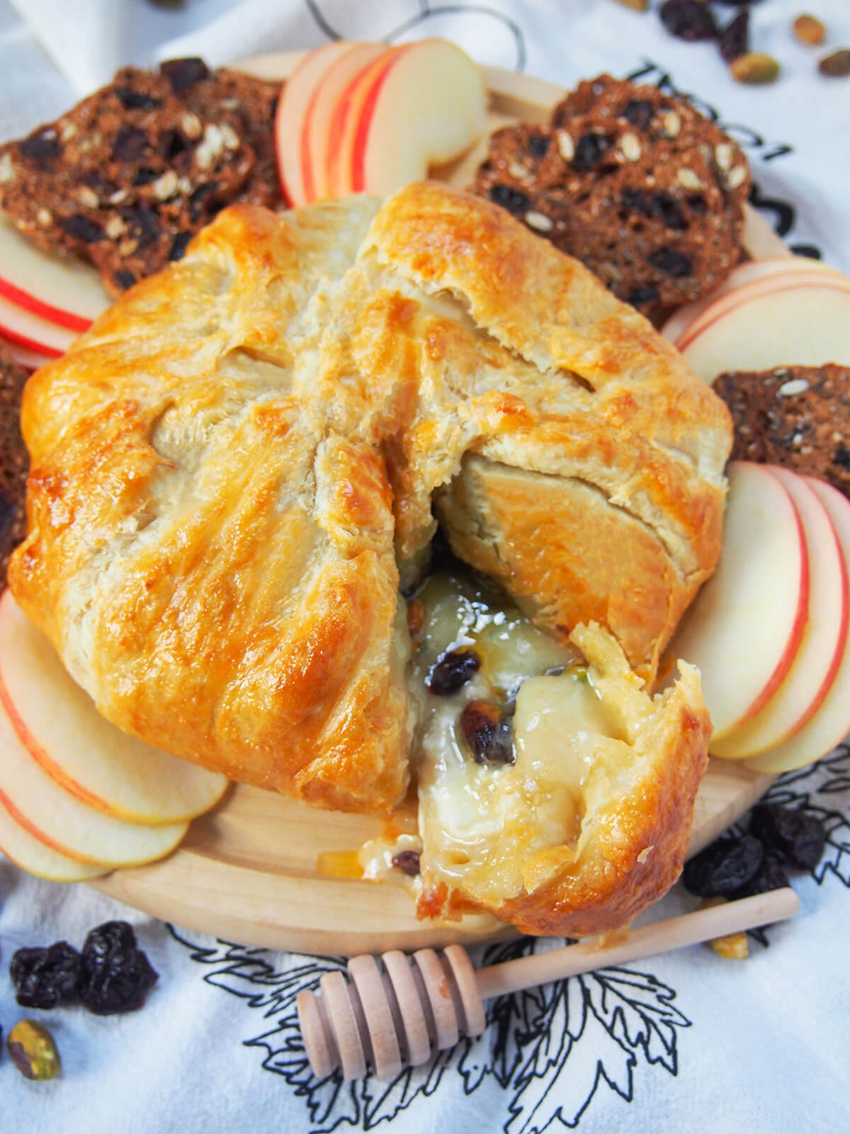 brie en croute with a wedge cut into it showing oozing cheese and dried fruit inside.
