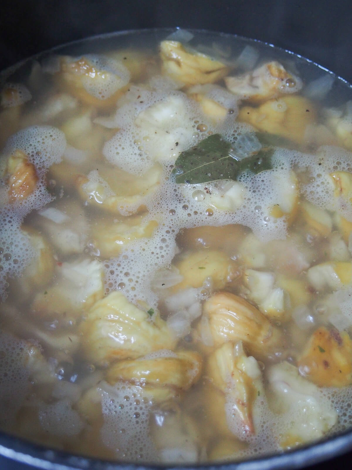 simmering chestnuts and onion in stock in pot.