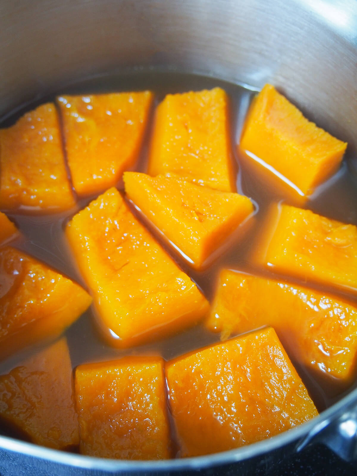 kabocha squash cooking in pot with stock.