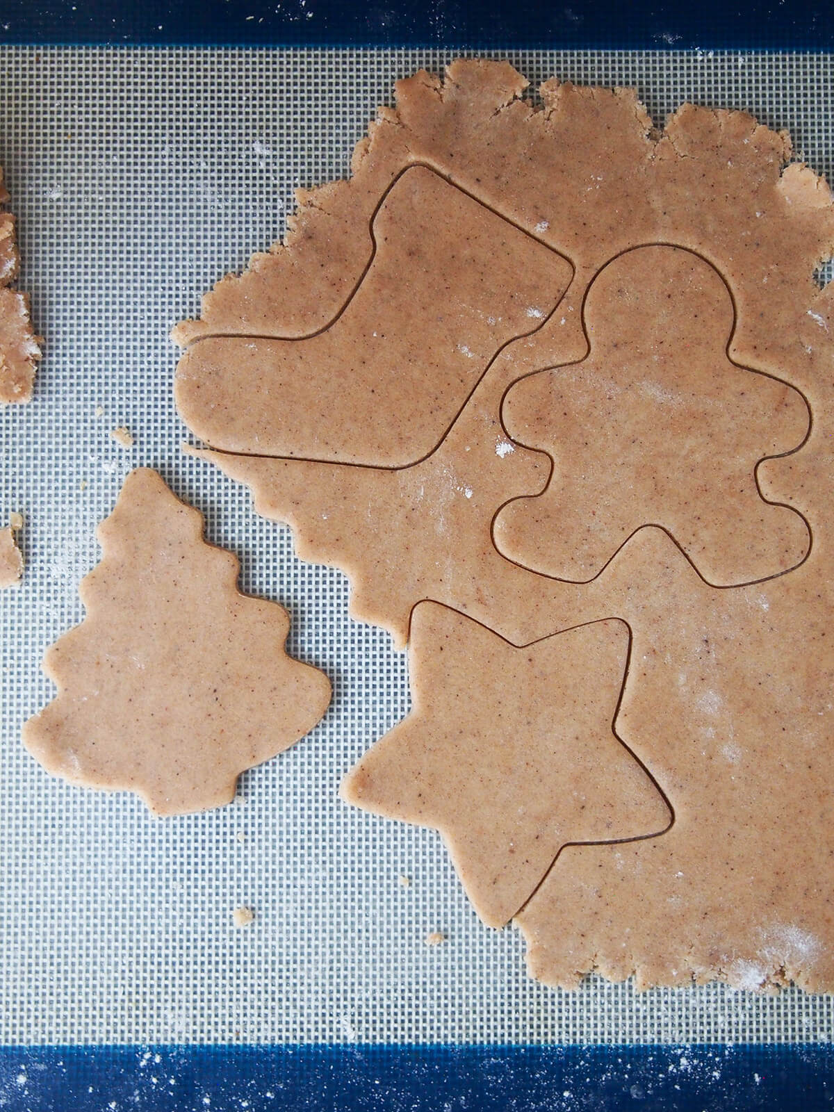 cutting out cookies on top of a silicone mat.